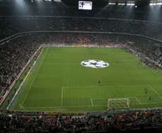 Un estadio de fútbol con una gran pantalla y un logotipo en el centro del campo de juego.