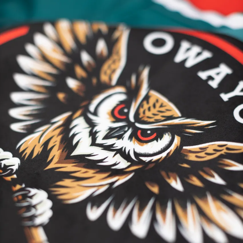 Un diseño detallado y colorido de un motivo de búho sobre un fondo negro, presentado en una prenda deportiva de owayo.