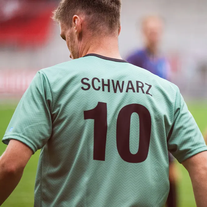 Un jugador lleva una camiseta de fútbol verde menta con el número 10 y el nombre 'SCHWARZ' en la parte posterior.