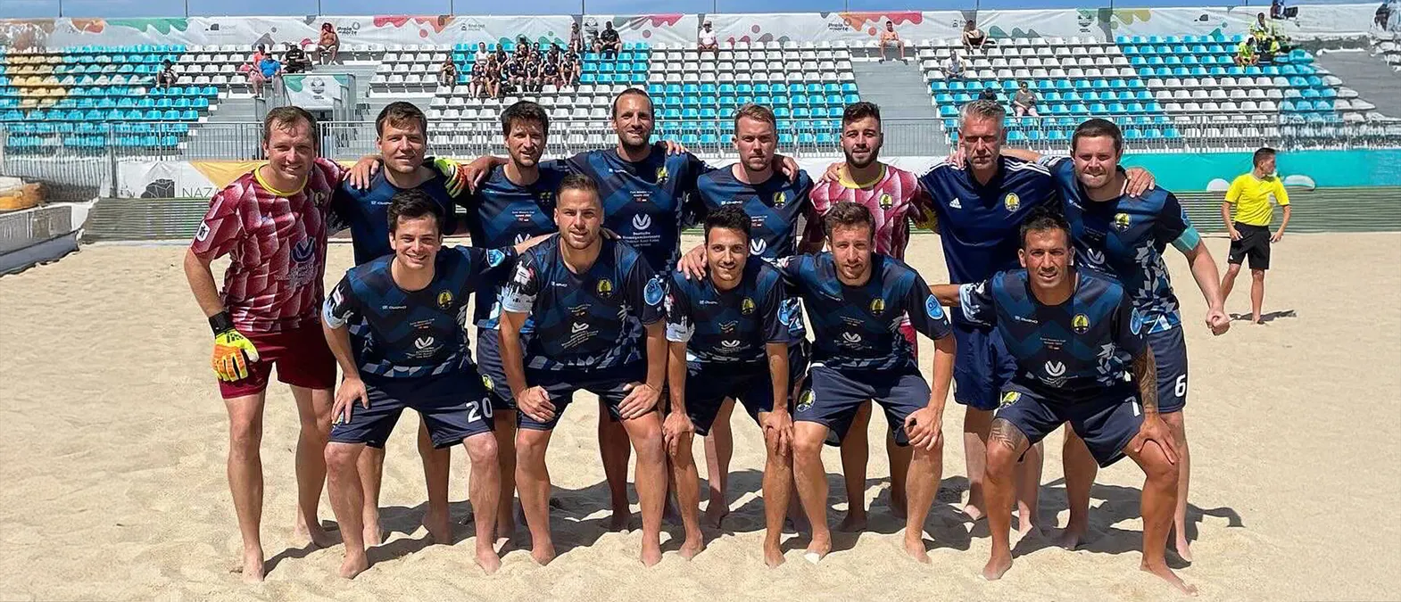 Un equipo de fútbol posa en una cancha de arena con ropa deportiva personalizada hecha por owayo.
