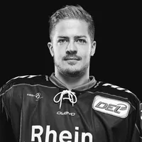 Un hombre con un jersey de hockey sobre hielo negro con el logo de owayo en el pecho y la palabra 'Rhein' en la parte delantera.