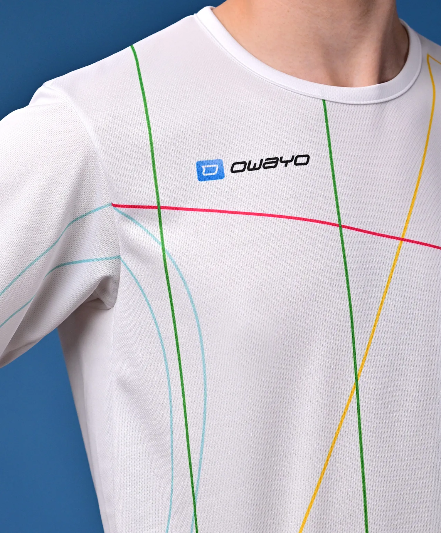 Una camiseta deportiva blanca con líneas diagonales de colores en verde, azul, rosa y amarillo, presentada sobre un fondo neutro.