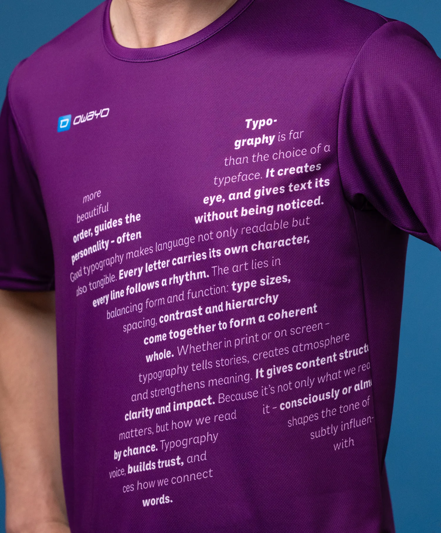 Un primer plano de una camiseta deportiva morada con varios textos tipográficos en la parte frontal, usada por un modelo.