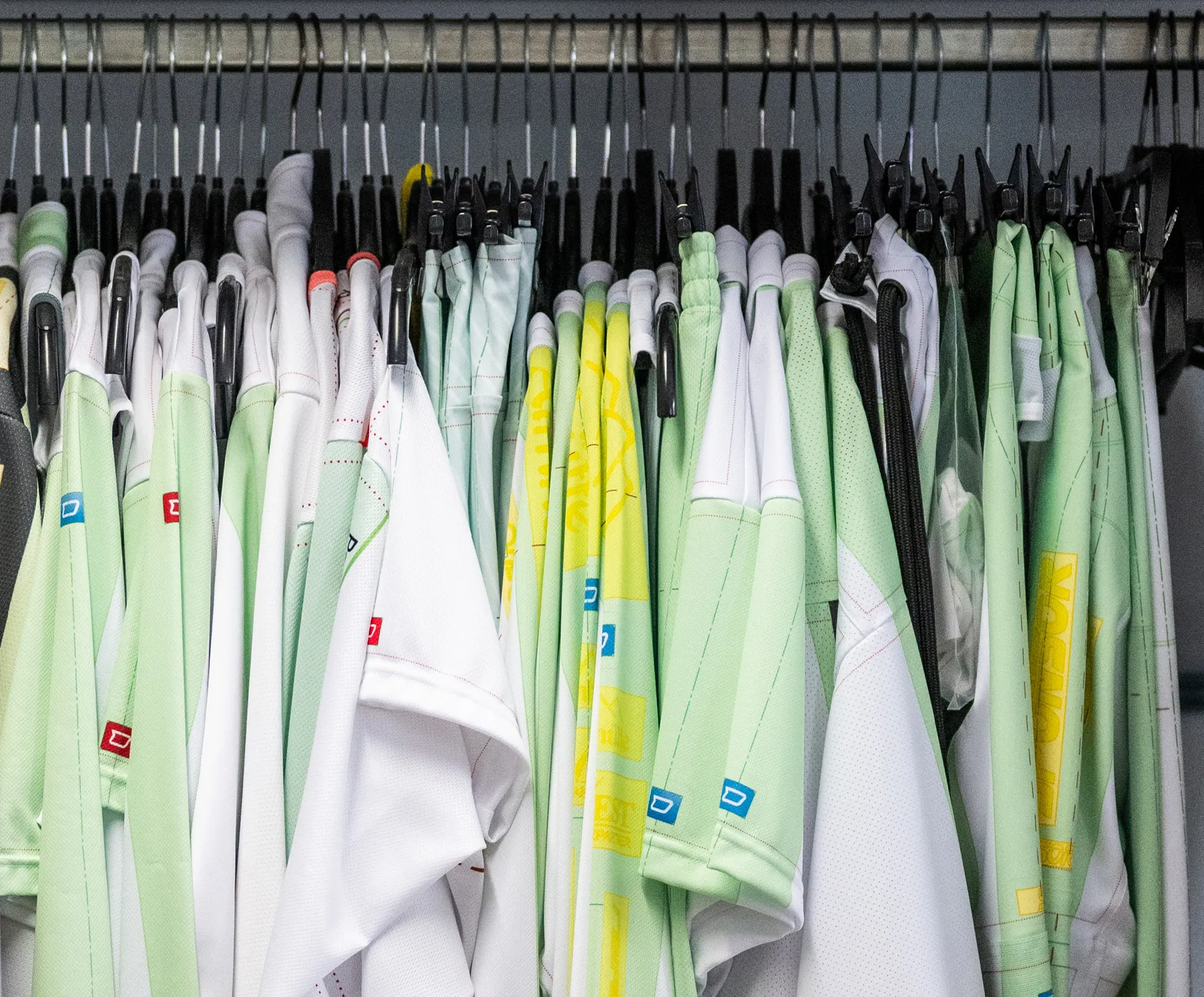 Una selección de ropa deportiva personalizada en varios colores colgando de perchas.