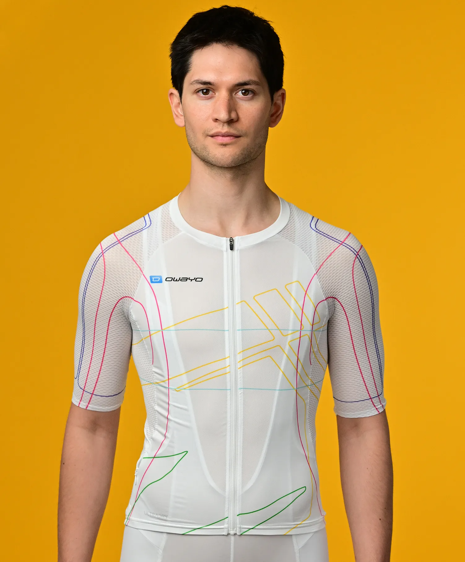 Un hombre lleva una camiseta deportiva blanca de manga corta con líneas de colores de owayo frente a un fondo amarillo.